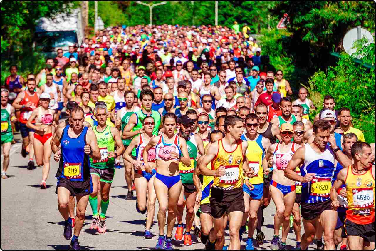 Athletes in various running gear and bib numbers pushing through a marathon course on a sunny day